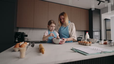joyful-woman-and-little-girl-are-cooking-dough-in-kitchen-mom-and-daughter-are-spending-time-together-in-home